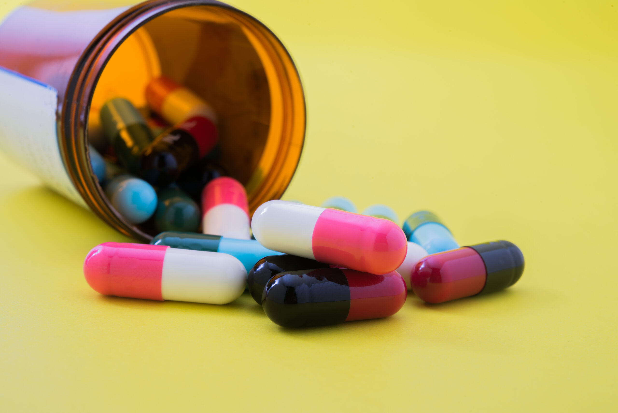Medical pills spilling out of a toppled from pill bottle